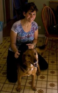 a young Steph Haddad in 2010, kneeling with a floppy-eared beagle german shepherd mix wagging his tail.